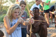 child shooting bow and arrow with San Bushmen